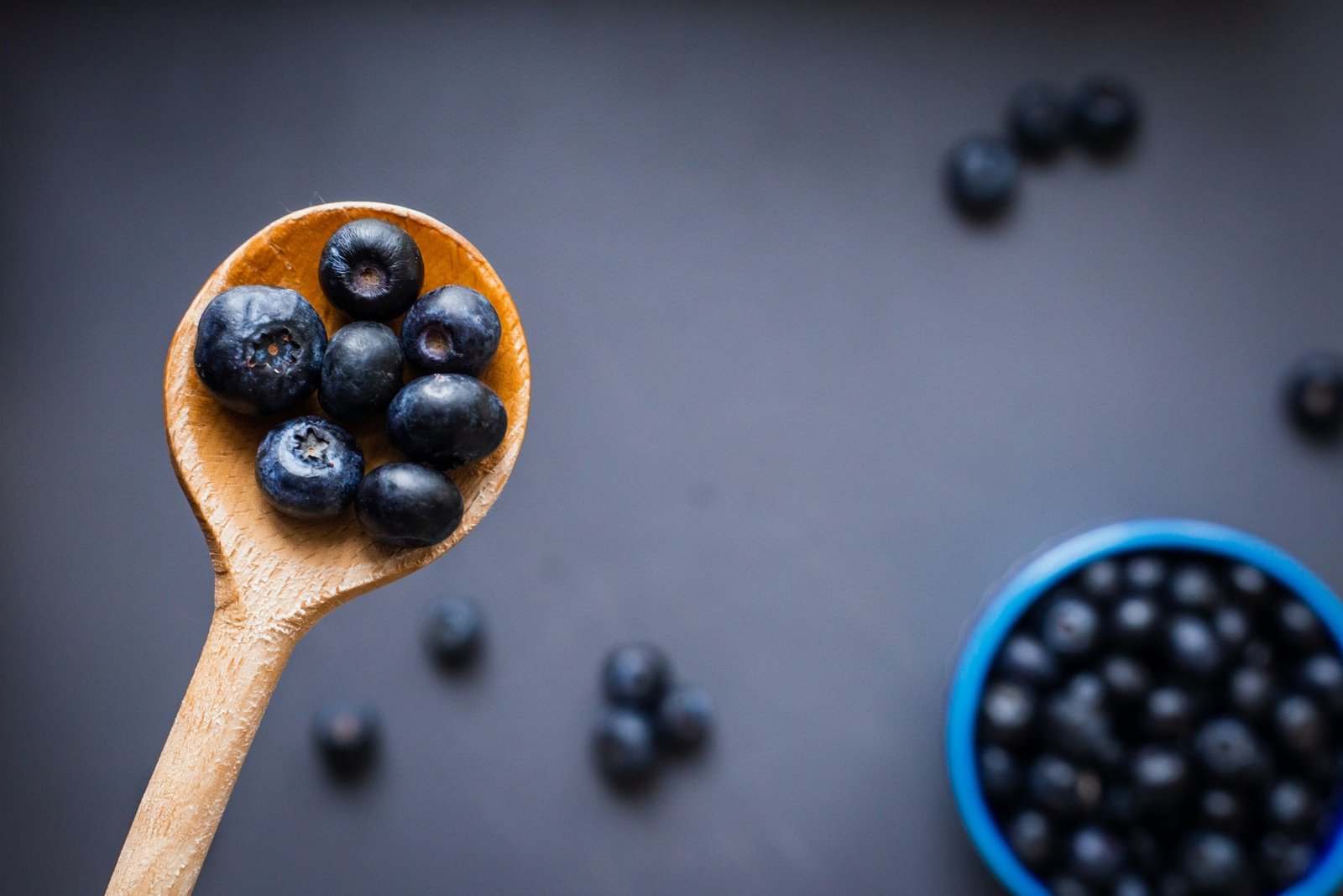 bowl and spoon of blueberries on purple backdrop
