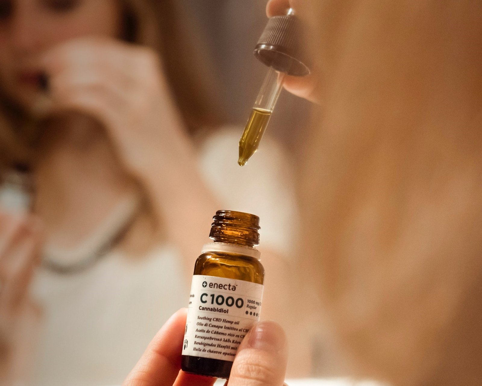 close up of woman using CBD oil bottle