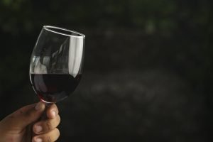 hand holding a glass of red wine with dark background