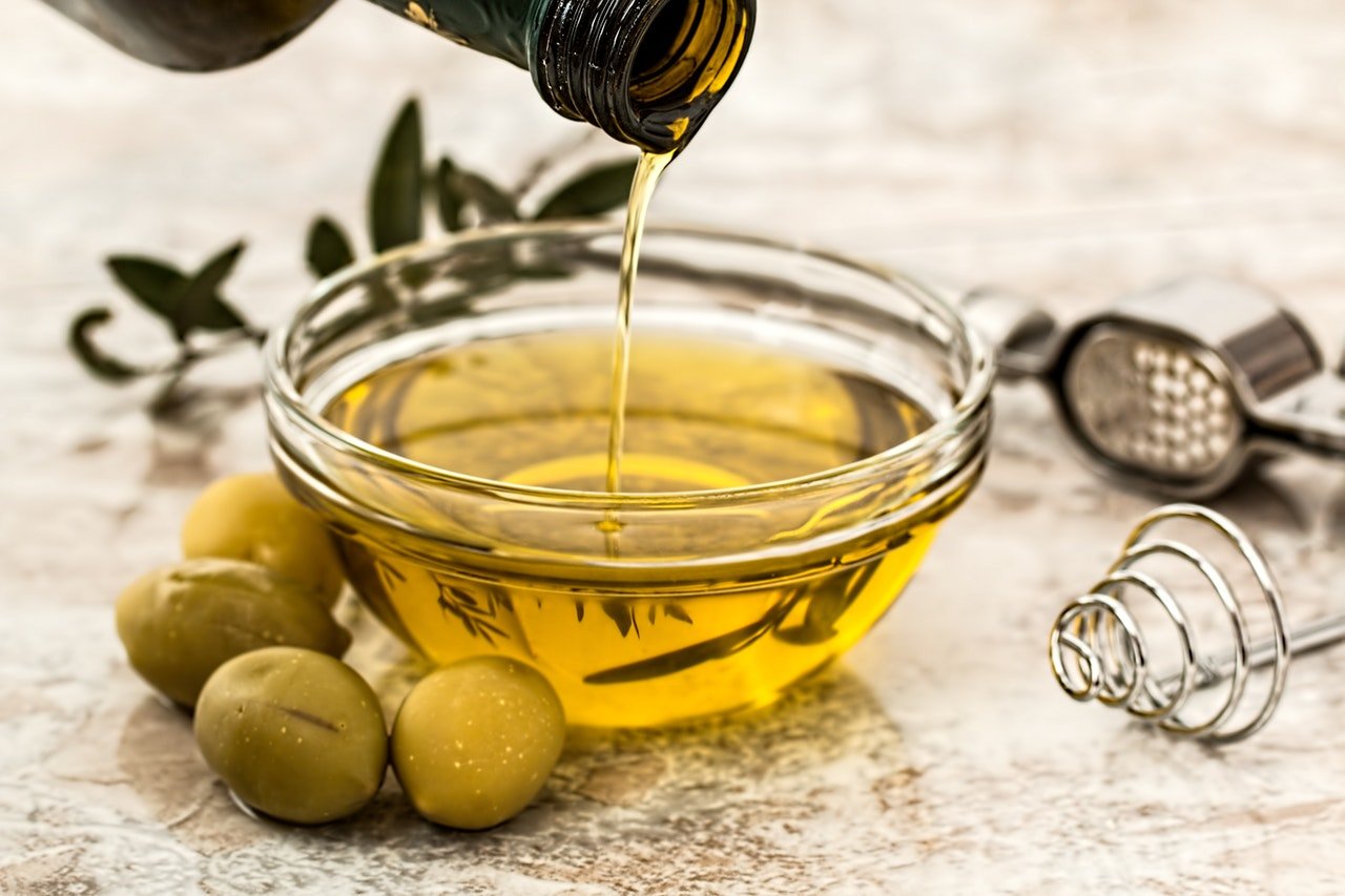 olive oil being poured into small glass bowl