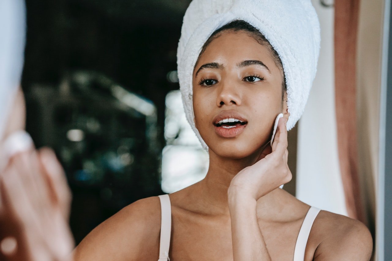 woman with hair in towel looking into mirror