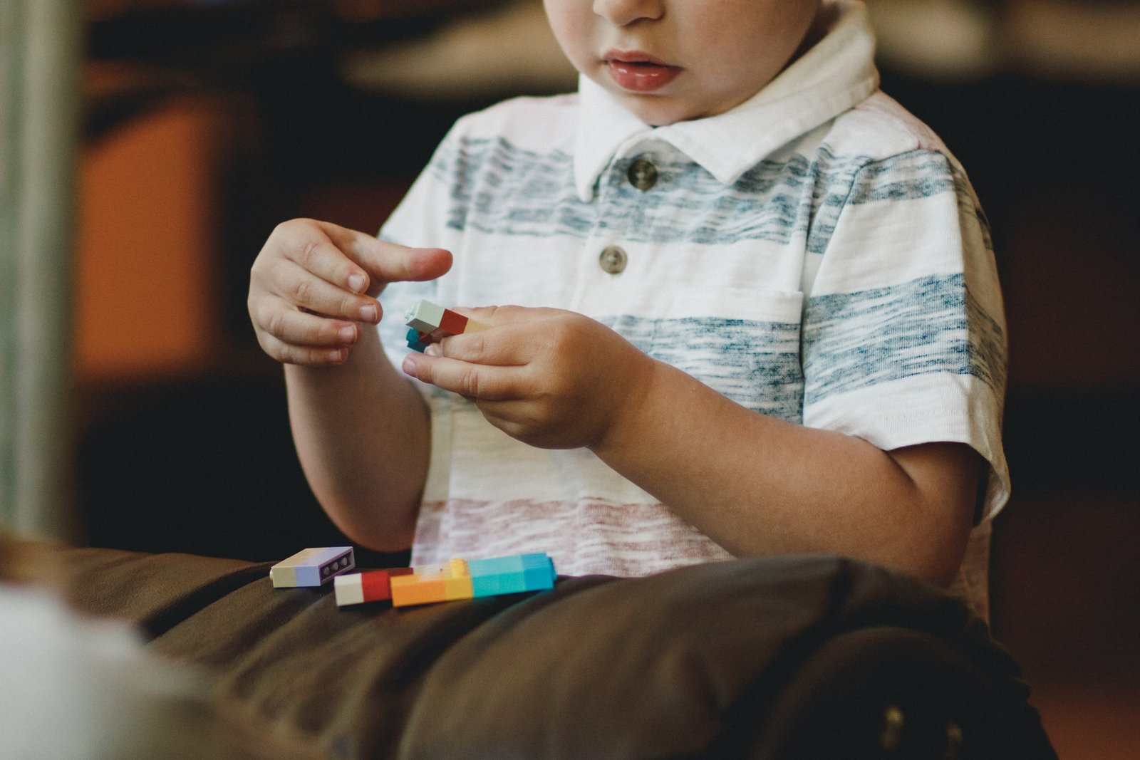 young boy playing with small plastic bricks
